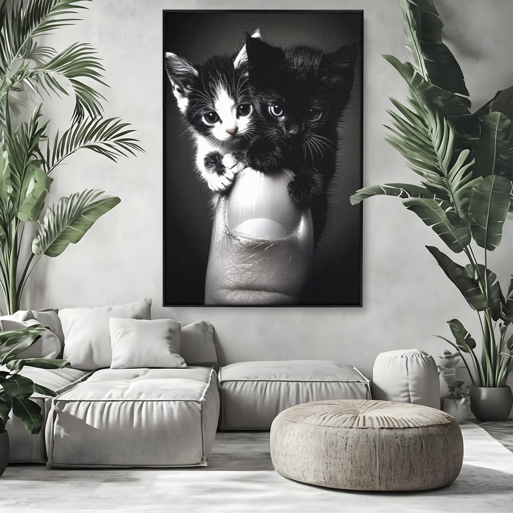 Tablou canvas cu tablou canvas cu doi pisoi mici agatati de un deget, in rama de aluminiu negru, pe perete intr-un living